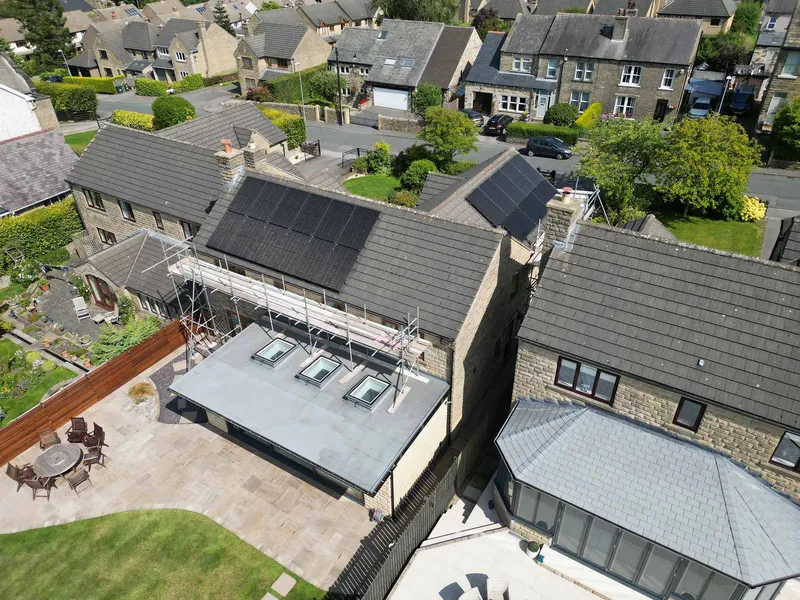 Aerial view of black solar arrays on the slate roofs of a stone-built street