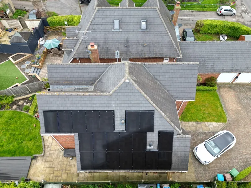 Aerial view of black solar arrays on two faces of a slate-roofed house